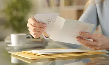 Girl hands opening an envelope on a desk at home.