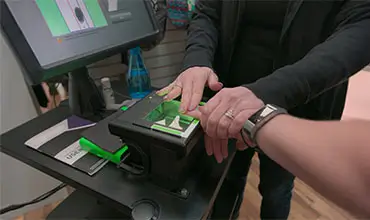 A young woman gets her finger prints scanned live.